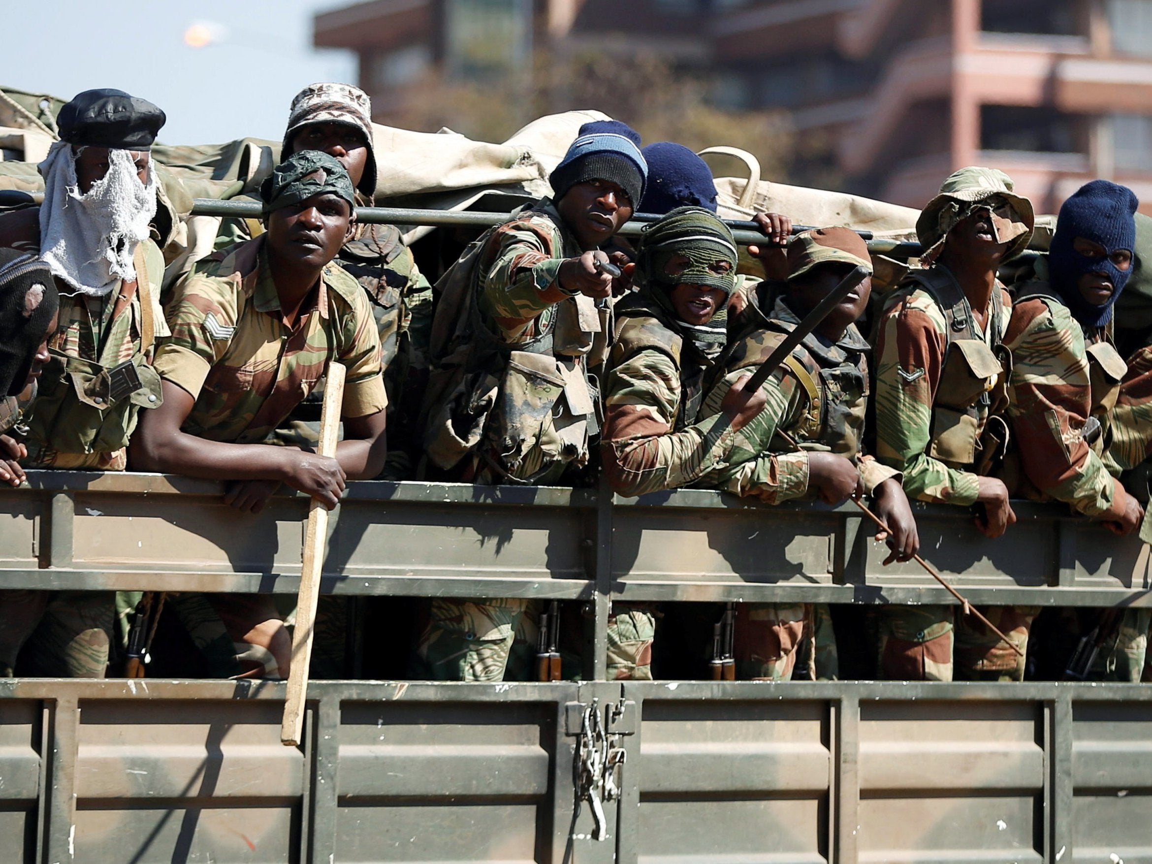 Members of the military gesture to the photographer as they patrol the streets of the capital Harare, Zimbabwe