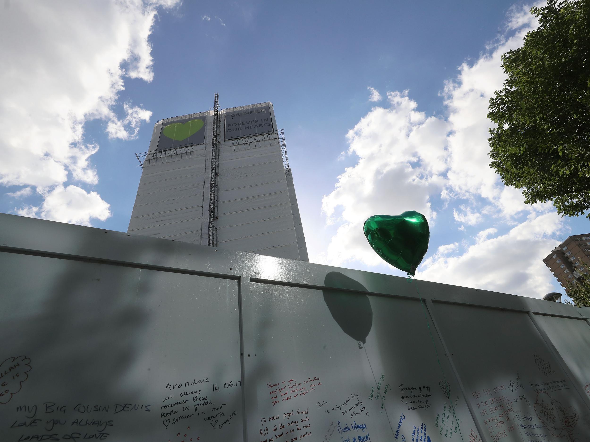 The tower's blackened shell has been covered with white plastic sheeting and banners featuring green heart since the one-year anniversary of the tragedy