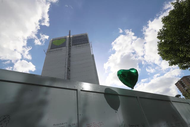 The tower's blackened shell has been covered with white plastic sheeting and banners featuring green heart since the one-year anniversary of the tragedy