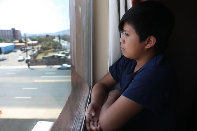 A young man, identified only as Manuel, looks out of his window he relaxes in his room at an Annunciation House facility after behing reunited with his father