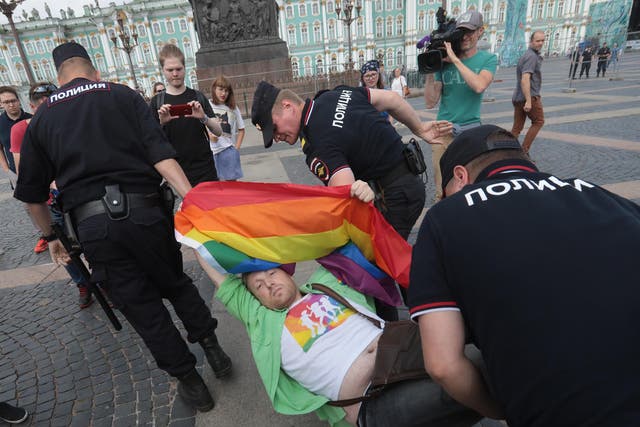 Three policemen were seen carrying one man who looked despondent but still held his multicoloured banner aloft above his head