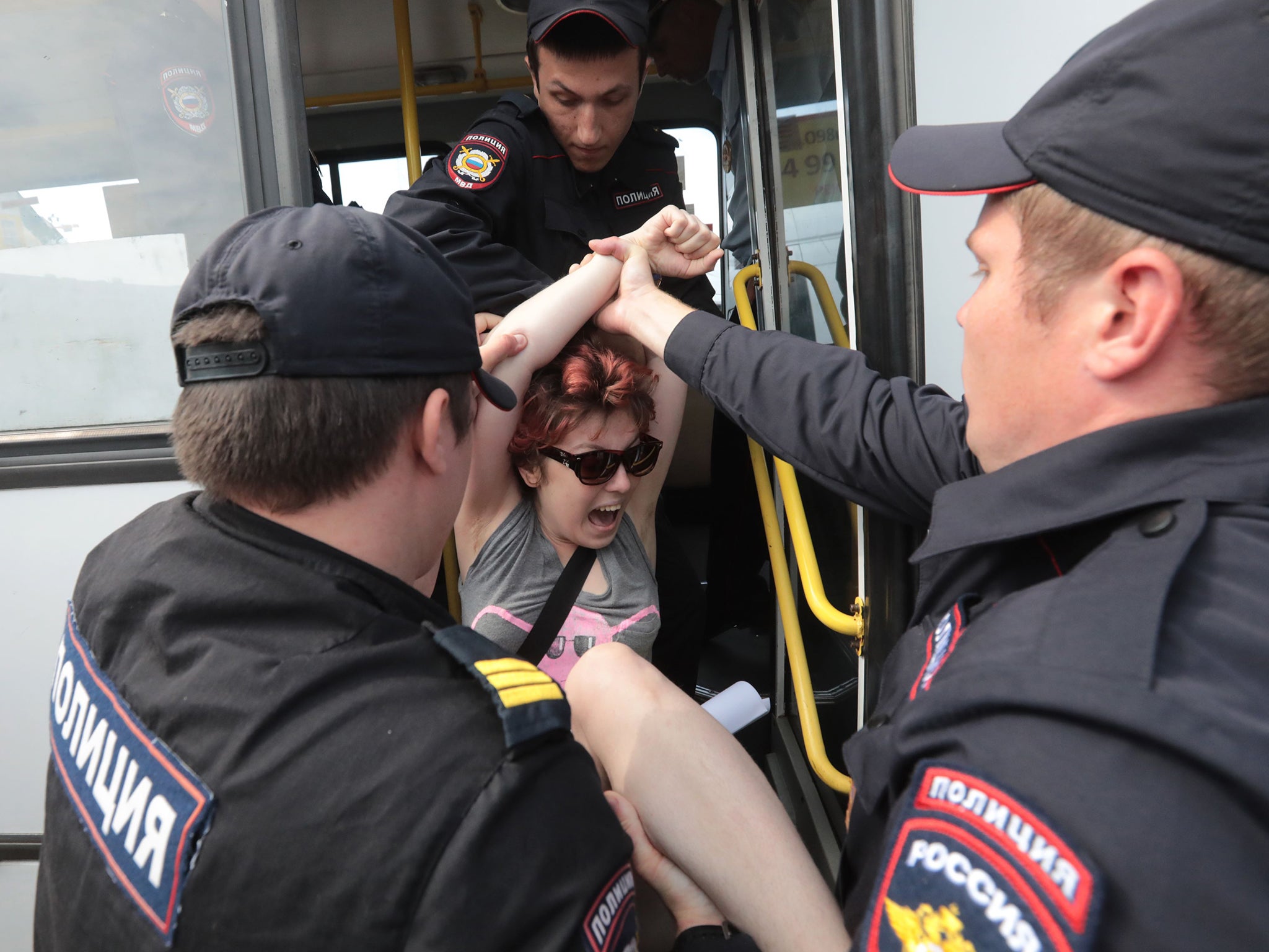 Police bundle an LGBT+ demonstrator onto a bus