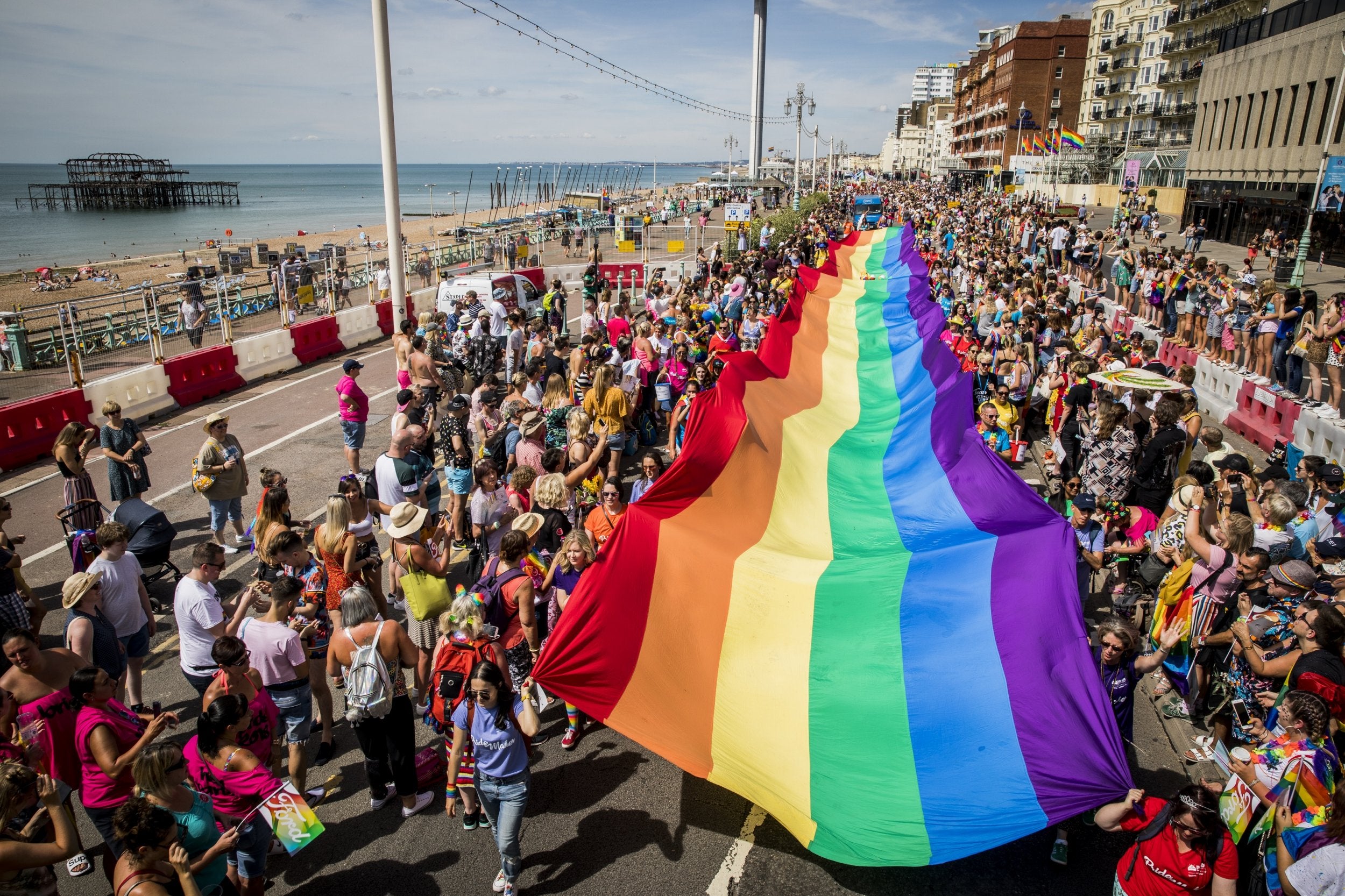 A giant rainbow flag is carried along the sea front during Brighton Pride