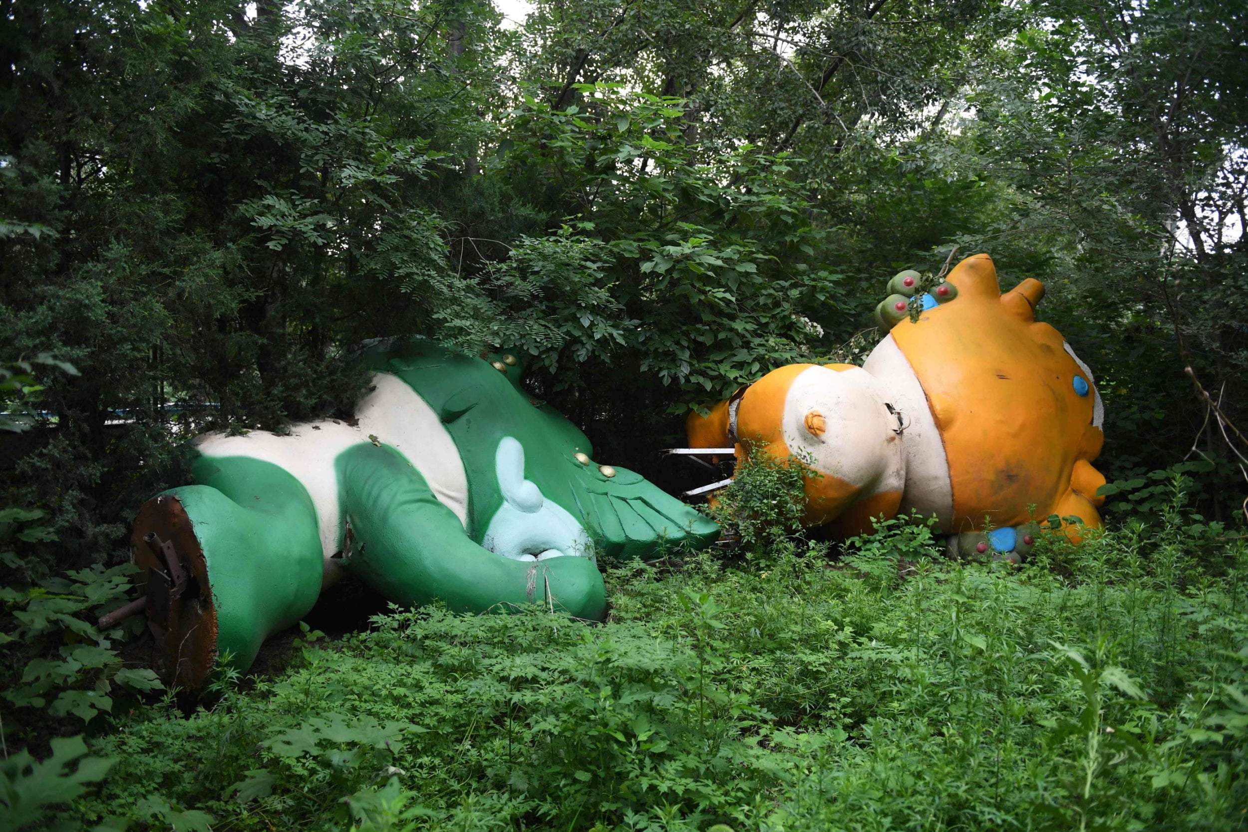This photo taken on July 20, 2018 shows Nini (L) and Yingying, two of the five mascots, lying among trees behind an abandoned, never-completed mall in Beijing