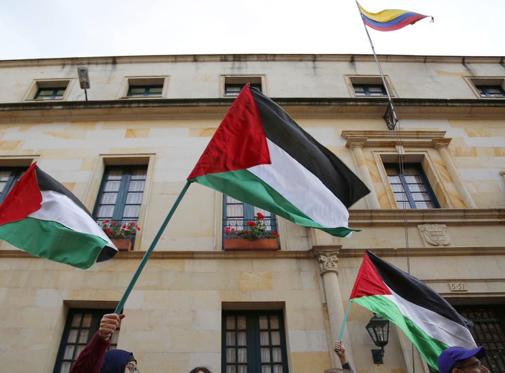 Demonstrators wave Palestinian flags during a protest outside the Foreign Ministry in Bogota