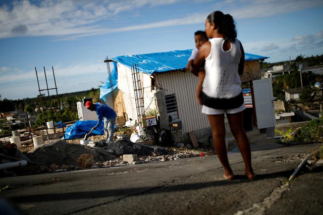 Samuel Vasquez rebuilds his house while his wife Ysamar Figueroa looks on