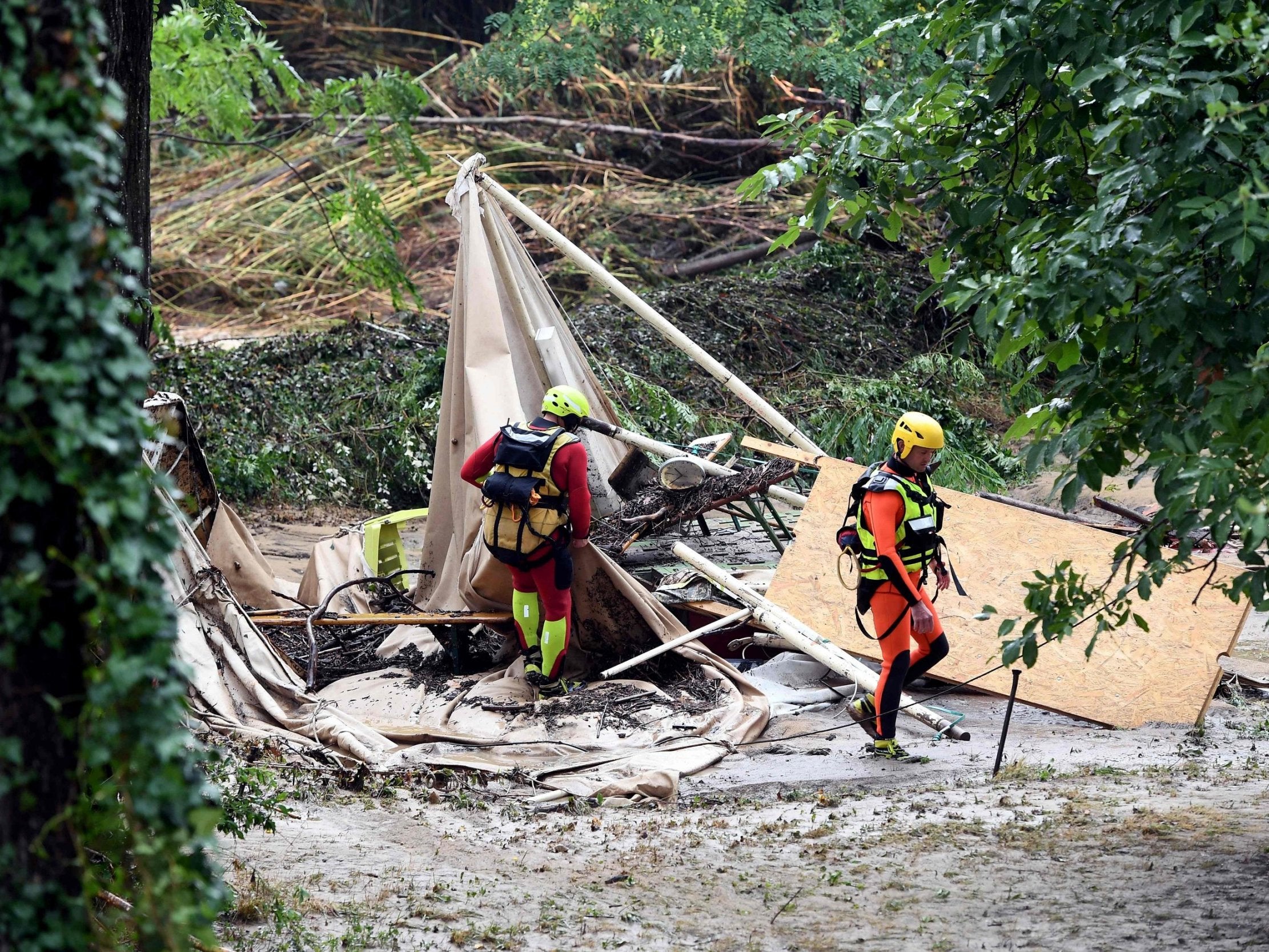 Rescuers walk past a damaged tent in a flooded campsite in France
