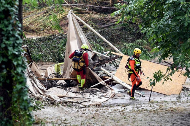 Rescuers walk past a damaged tent in a flooded campsite in France