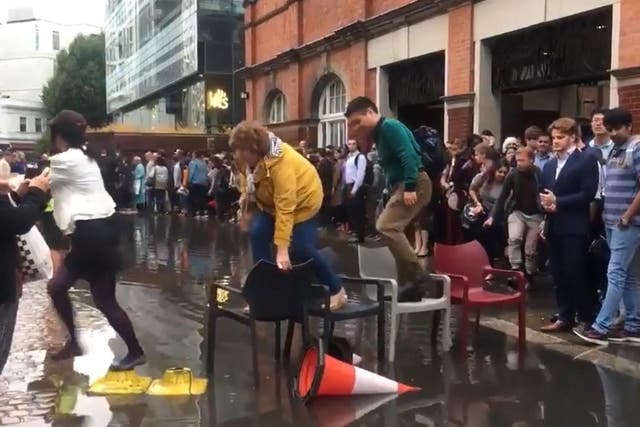 London commuters cross a puddle using chairs