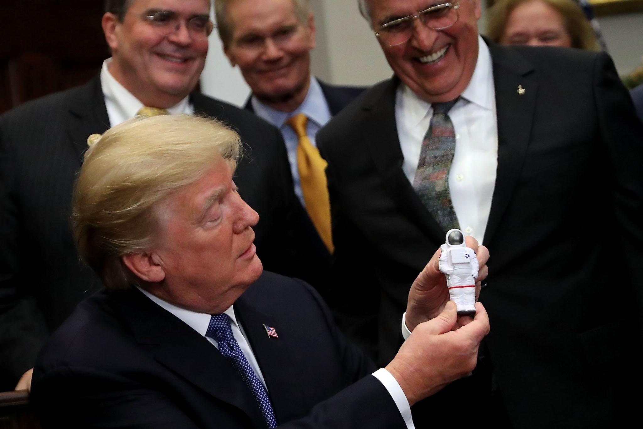 U.S. President Donald Trump holds a plastic astronaut figurine given to him by Apollo 17 astronaut and former U.S. Senator Jack Schmitt during a signing ceremony for 'Space Policy Directive 1' in the Roosevelt Room at the White House December 11, 2017 in Washington