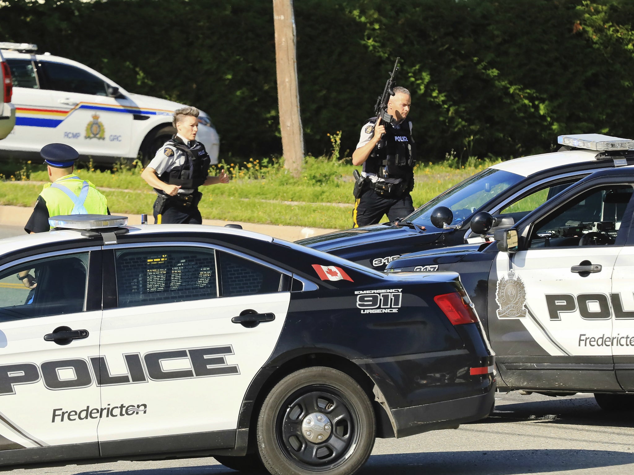 Police and RCMP officers survey the area of a shooting in Fredericton, New Brunswick, Canada on 10 August 2018.