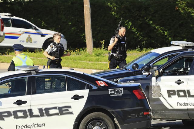 Police and RCMP officers survey the area of a shooting in Fredericton, New Brunswick, Canada on 10 August 2018.