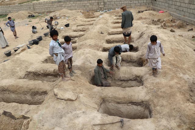 Boys inspect graves prepared for victims of an air strike in Saada province, Yemen, which killed 40 children on their way to school