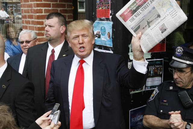 Donald Trump holds up a newspaper as he makes a reference to a story in it while walking through downtown Portsmouth, New Hampshire.