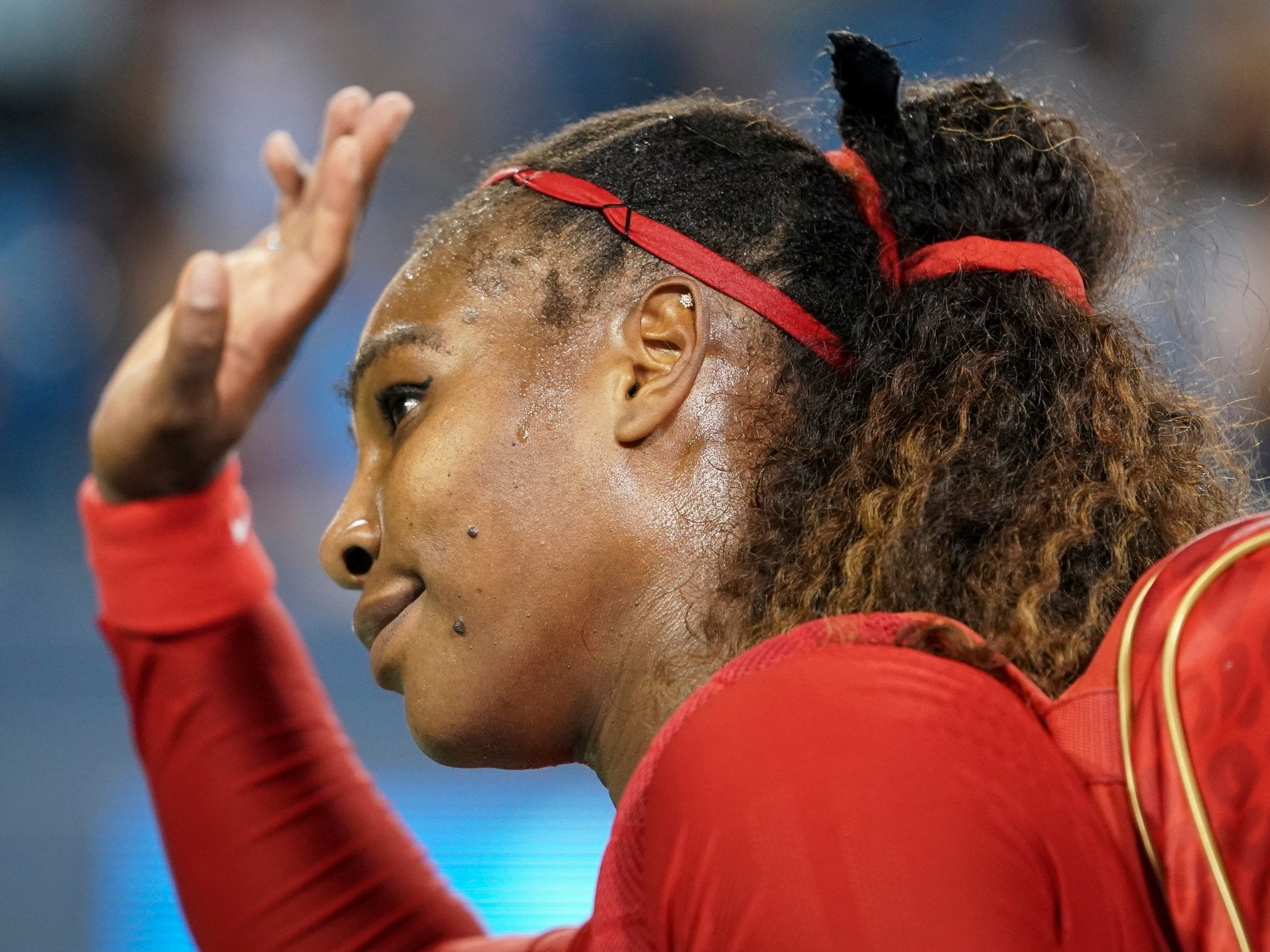 Serena Williams weaves to fans as she leaves the court following defeat