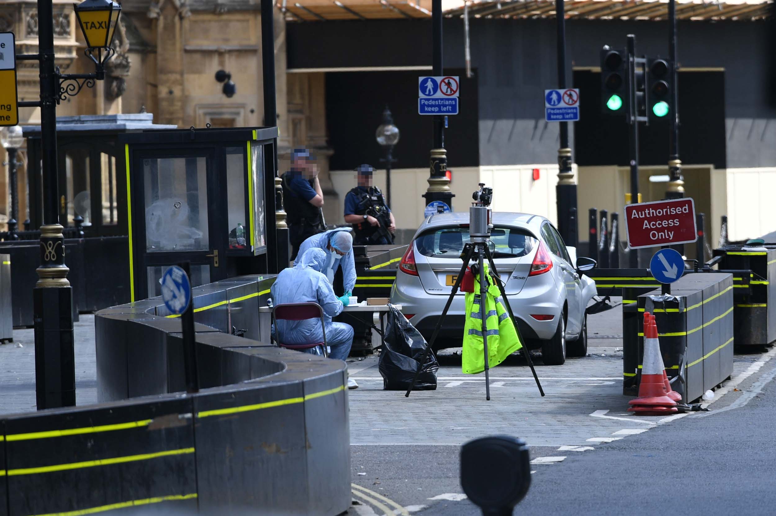 Forensic officers examine the car that crashed into the security barriers