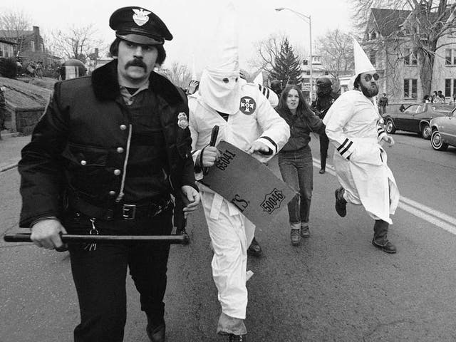 Ku Klux Klan members are escorted away from protesters by police in Meriden, Connecticut, 1981