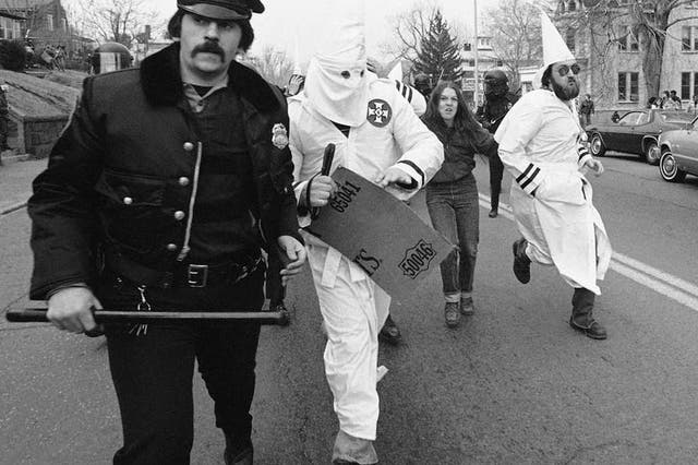 Ku Klux Klan members are escorted away from protesters by police in Meriden, Connecticut, 1981