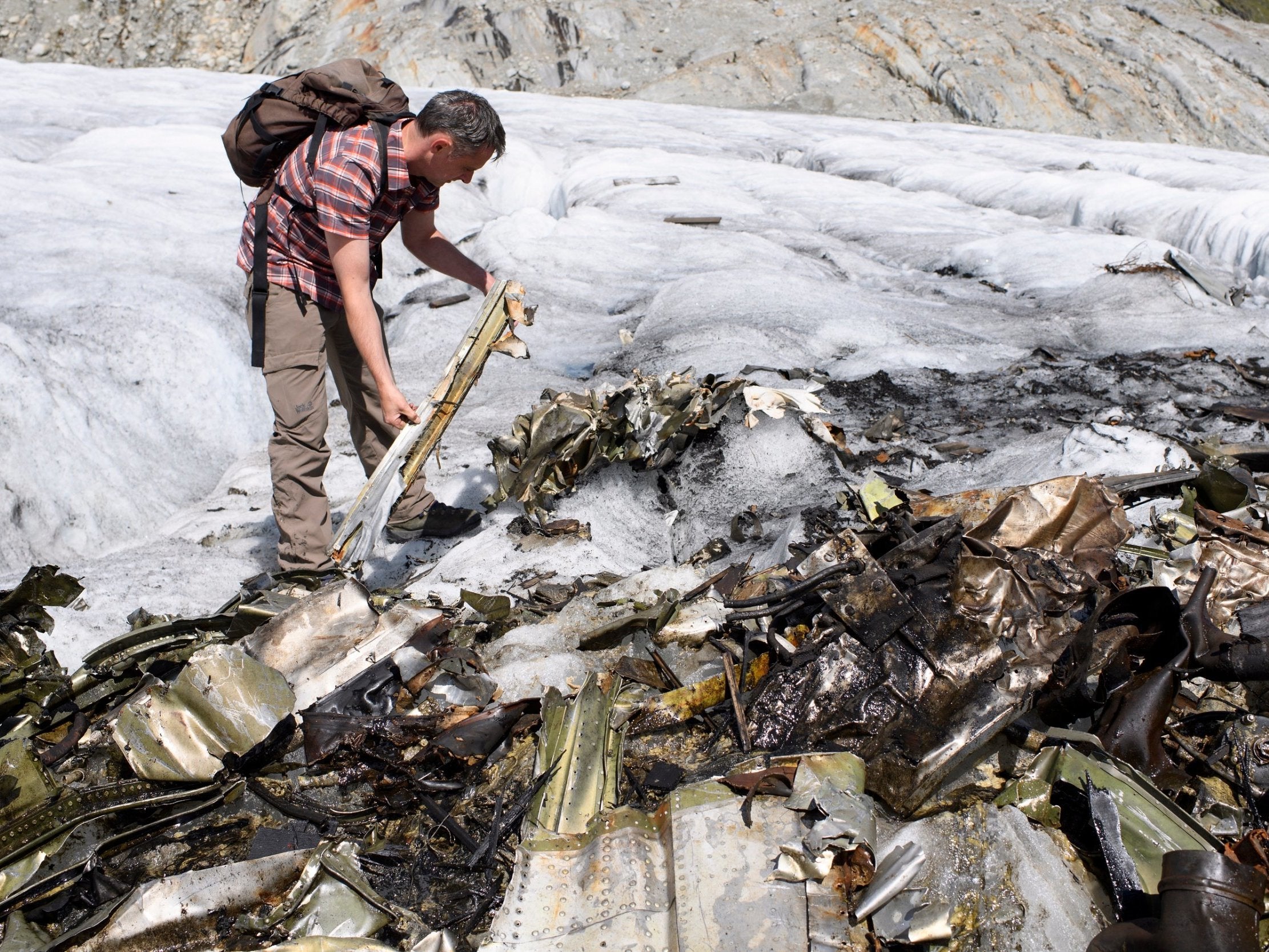 Adriano Boschetti, head of Archaeological Service Bern, looks through the wreckage debris of the WW2 plane