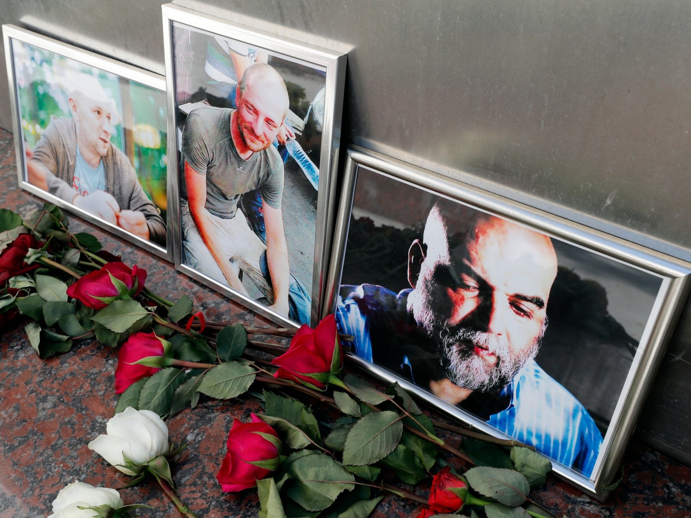 Flowers are placed as a last tribute in front of the photographs of Russian journalists Alexander Rastorguyev (L), Kirill Radchenko (C) and Orkhan Dzhemal (R) outside the Central House of Journalists in Moscow, Russia