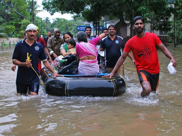 Indian volunteers and rescue personnel evacuate local residents in a boat in a residential area at Kozhikode, in the Indian state of Kerala