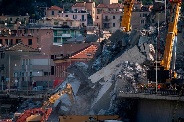 Rescuers work among the rubble and wreckage of the Morandi motorway bridge in Genoa