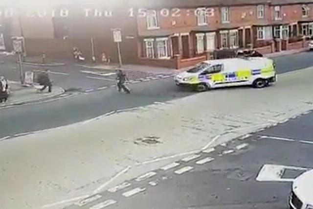 A police officer gives chase seconds before he is run over by a colleague in a police van