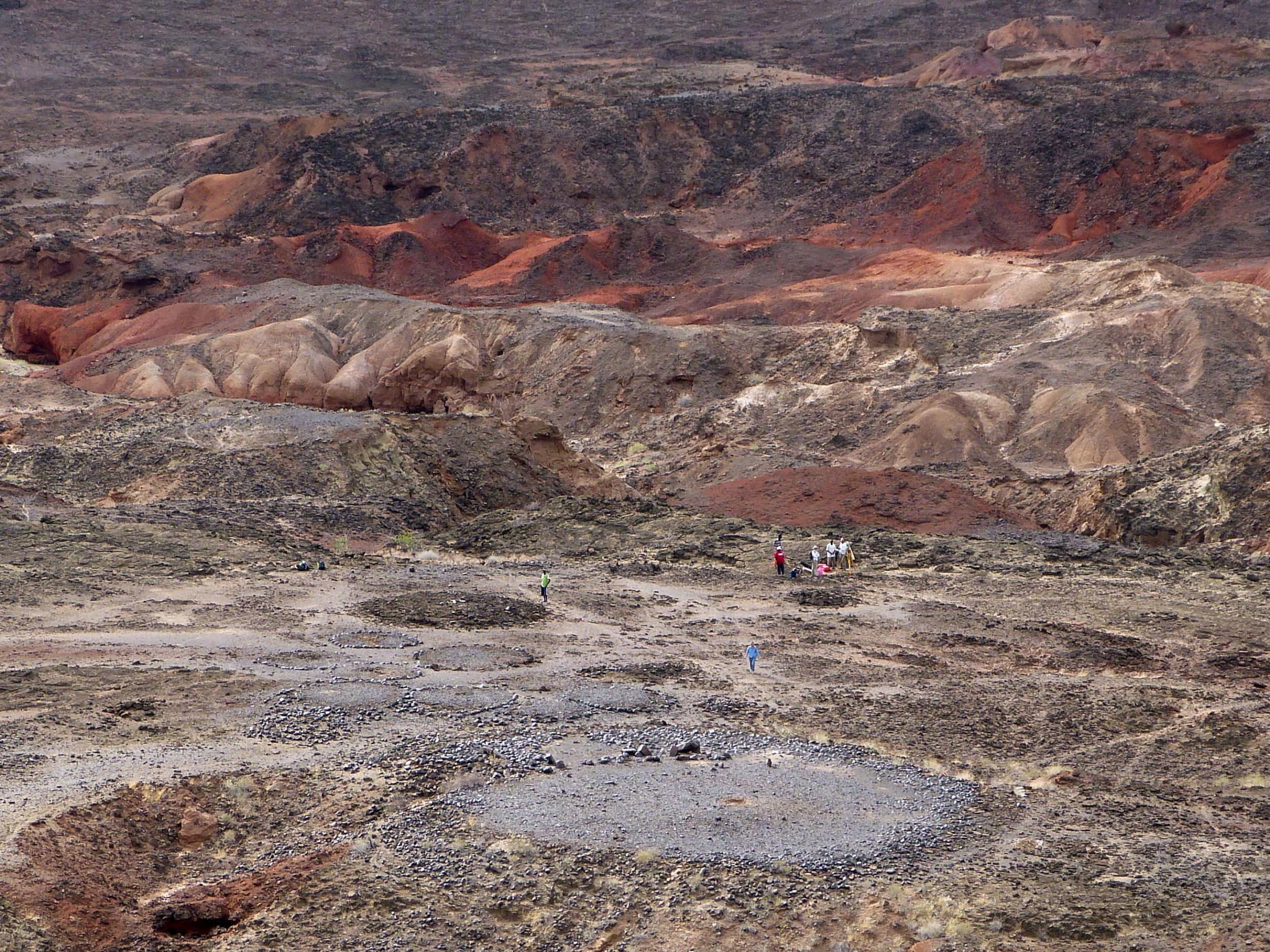 View from the high volcanic ridge overlooking Lothagam North Pillar site. In the foreground, the 30m platform contains the mortuary cavity, and is ringed by boulders, with a linear arrangement of pillars on its east side