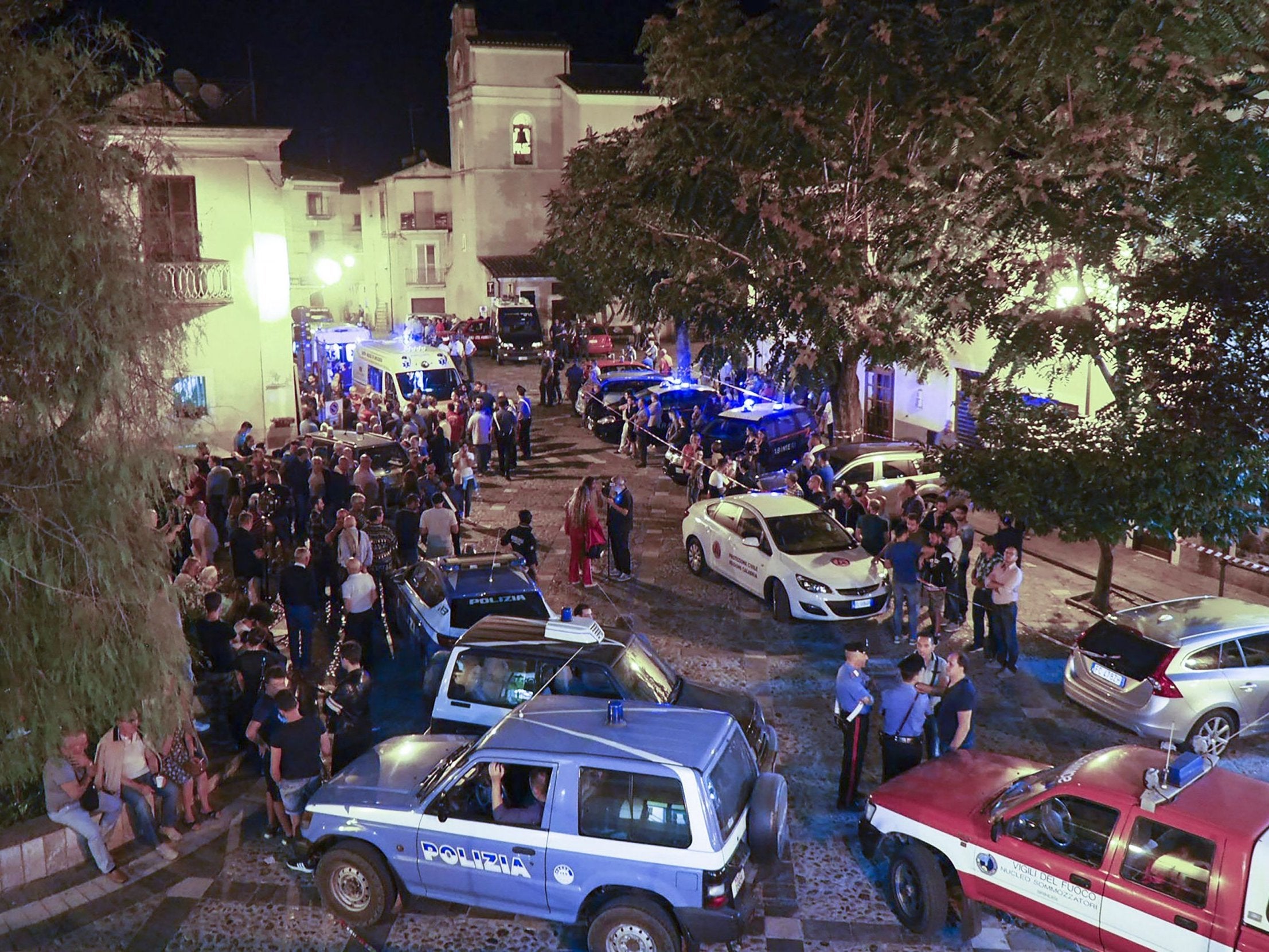 Rescuers and citizens wait in the central square of Civita as rescue squads worked through the night with spotlights