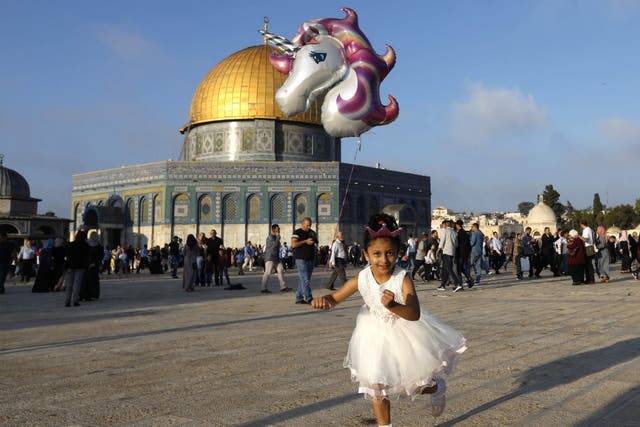 A young Palestinian girl flies a balloon near the Dome of the Rock at al-Aqsa Mosque compound in Jerusalem's old city on the first day of Eid al-Adha
