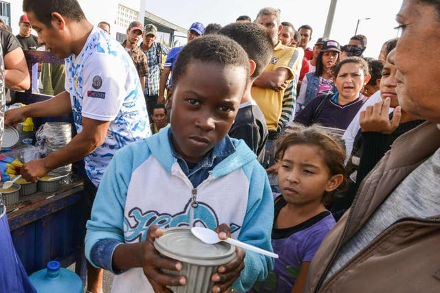 Venezuelan nationals receive food from religious volunteers while they wait for an authorisation that will allow them to enter Peru. 