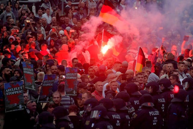 Far-right protesters brandish ‘Stop asylum’ placards at a rally in Chemnitz as a line of police officers watch on
