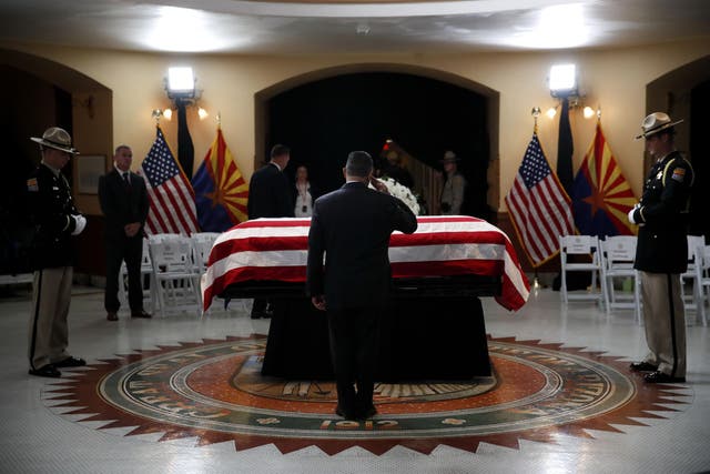 A serviceman pays his respects at the casket of US Senator John McCain during a memorial service at the Arizona Capitol
