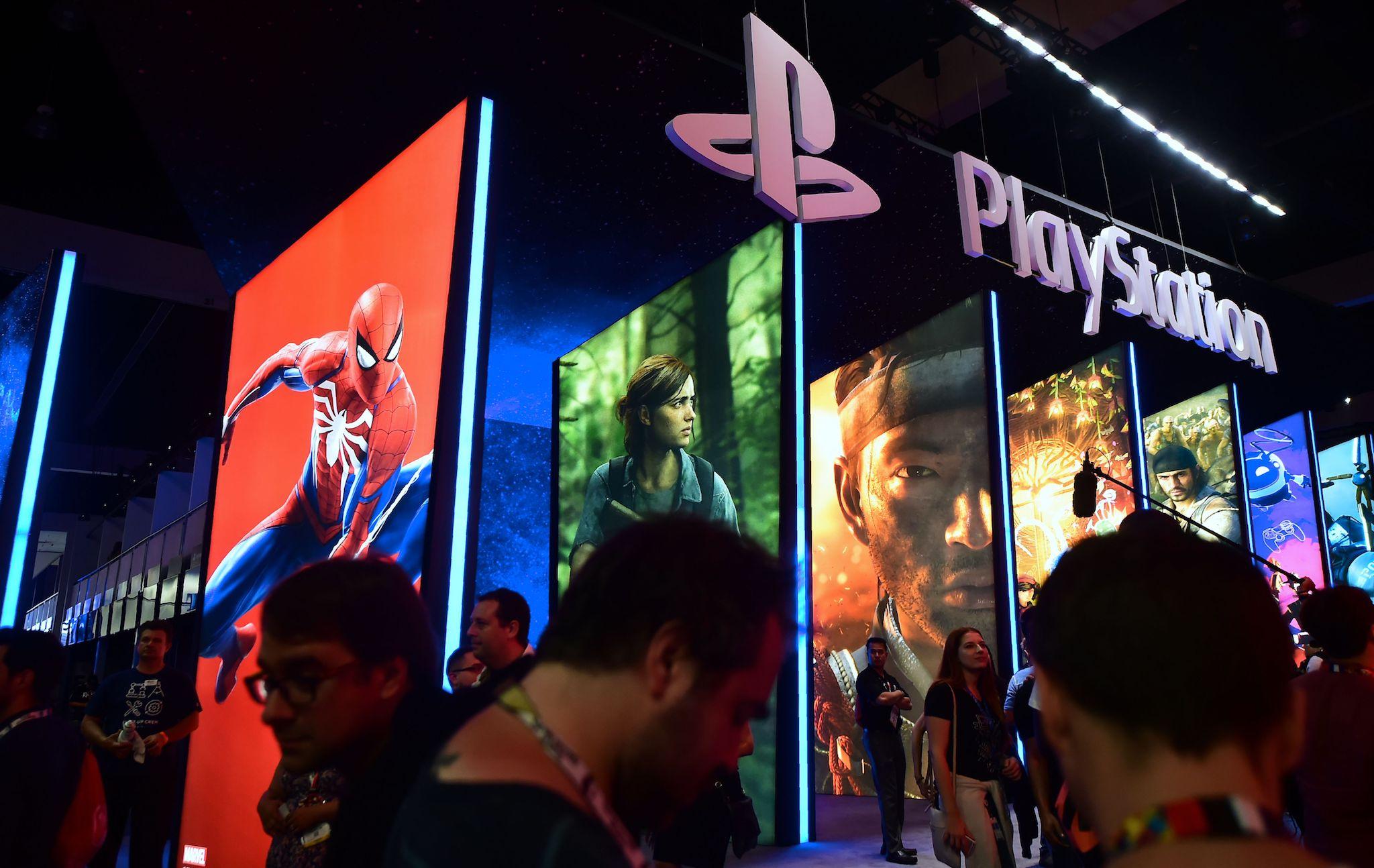 People wander in front of the Playstation posters at the 24th Electronic Expo, or E3 2018, in Los Angeles, California on June 12, 2018, where hardware manufacturers, software developers and the video game industry present their new games