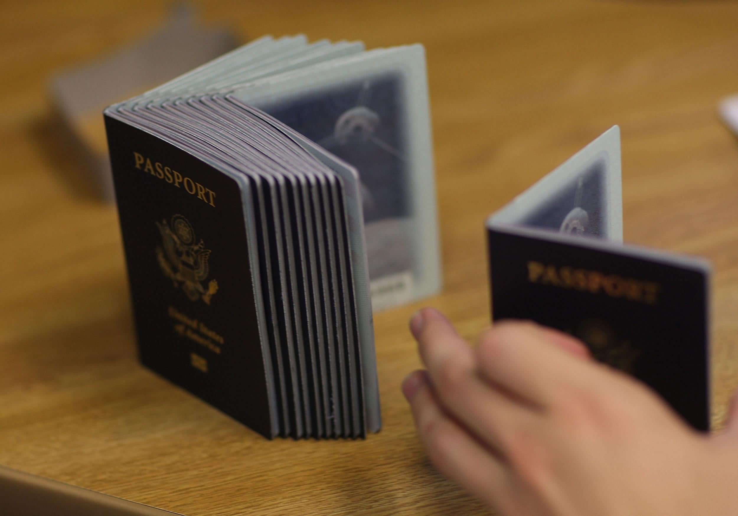 A Passport Processing employee uses a stack of blank passports to print a new one at the Miami Passport Agency