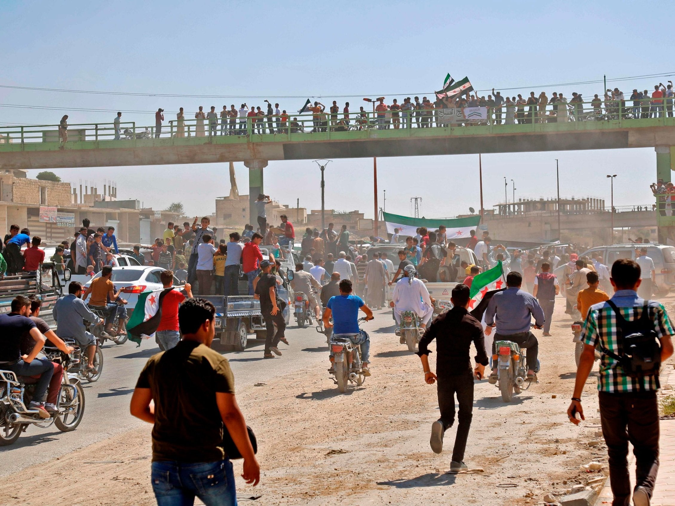 Syrians chant slogans and wave flags of the opposition as they protest against the regime and its ally Russia, in the rebel-held town of Maarrat al-Numan in the north of Idlib province