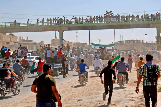 Syrians chant slogans and wave flags of the opposition as they protest against the regime and its ally Russia, in the rebel-held town of Maarrat al-Numan in the north of Idlib province