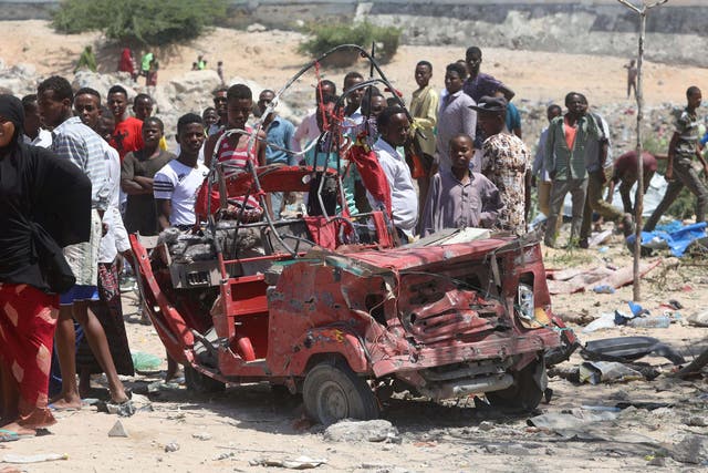Civilians look at the remain of a rickshaw destroyed at the site of a blast in the district office of Hawlwadag in Mogadishu, Somalia.