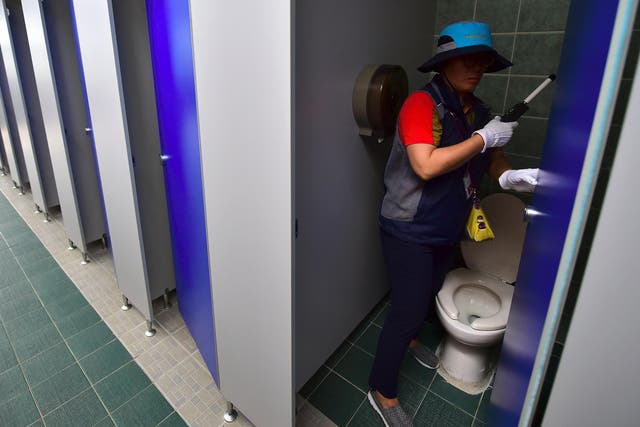 Staff check a public toilet in Seoul for hidden cameras
