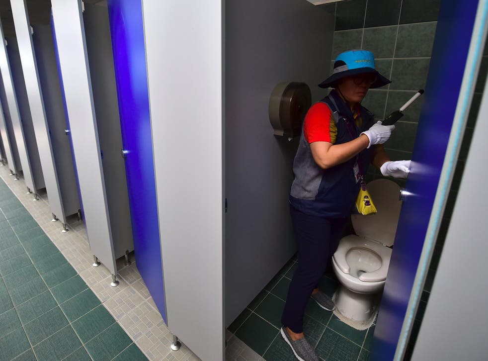 Staff check a public toilet in Seoul for hidden cameras
