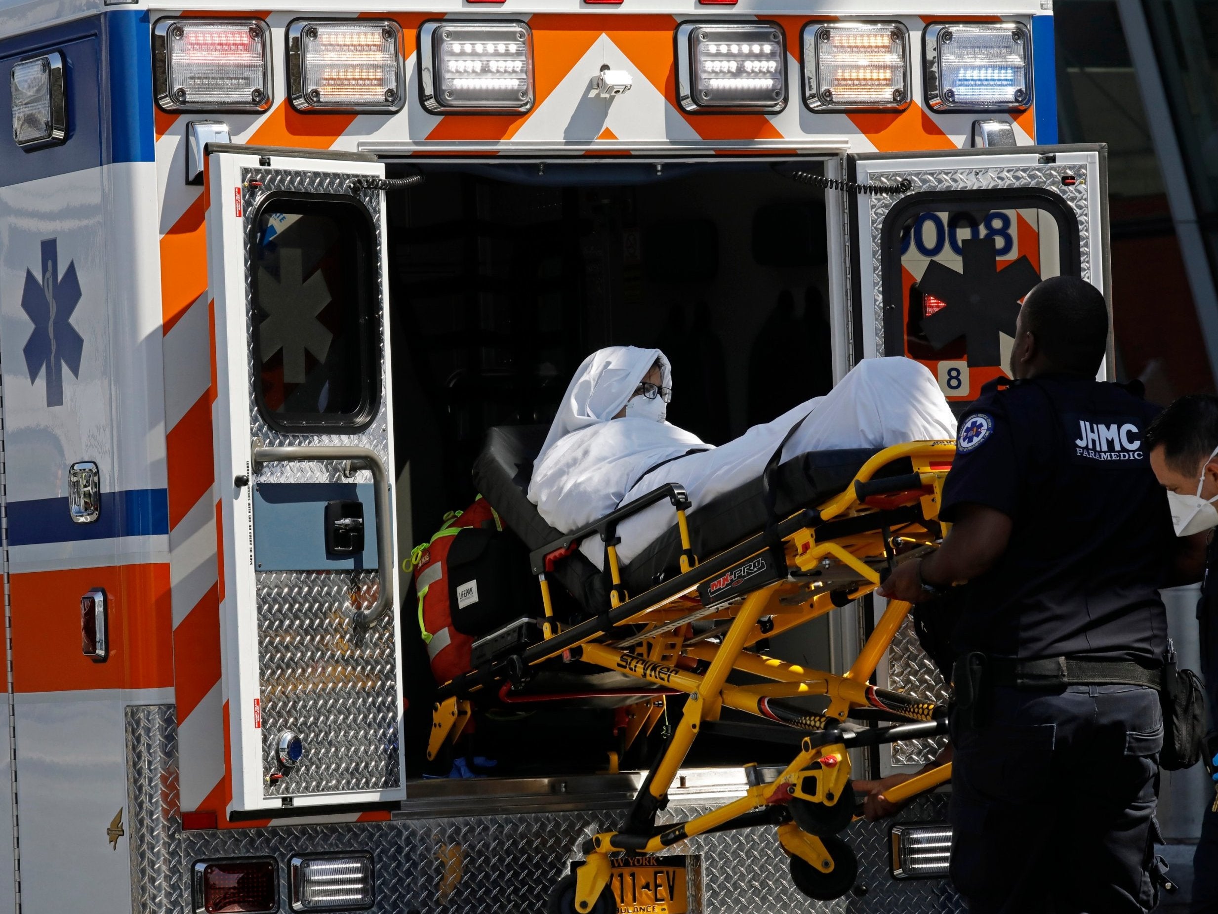 A passenger is taken from a quarantined plane onto an ambulance at JFK airport