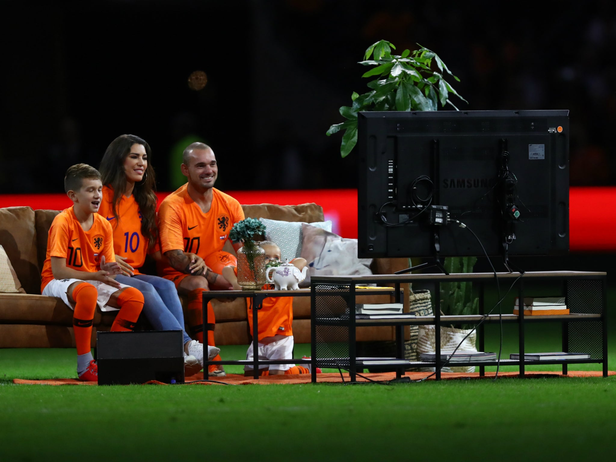 Wesley Sneijder watches TV tributes from a sofa on the pitch with family after final Netherlands appearance