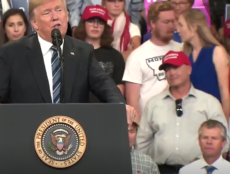 Woman in blue dress tells two men over Donald Trump's left shoulder to leave