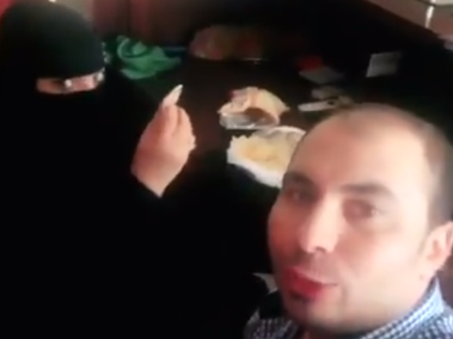 The footage shows a woman dressed in a burqa eating breakfast with a man