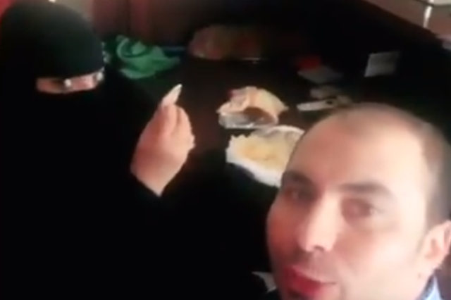 The footage shows a woman dressed in a burqa eating breakfast with a man