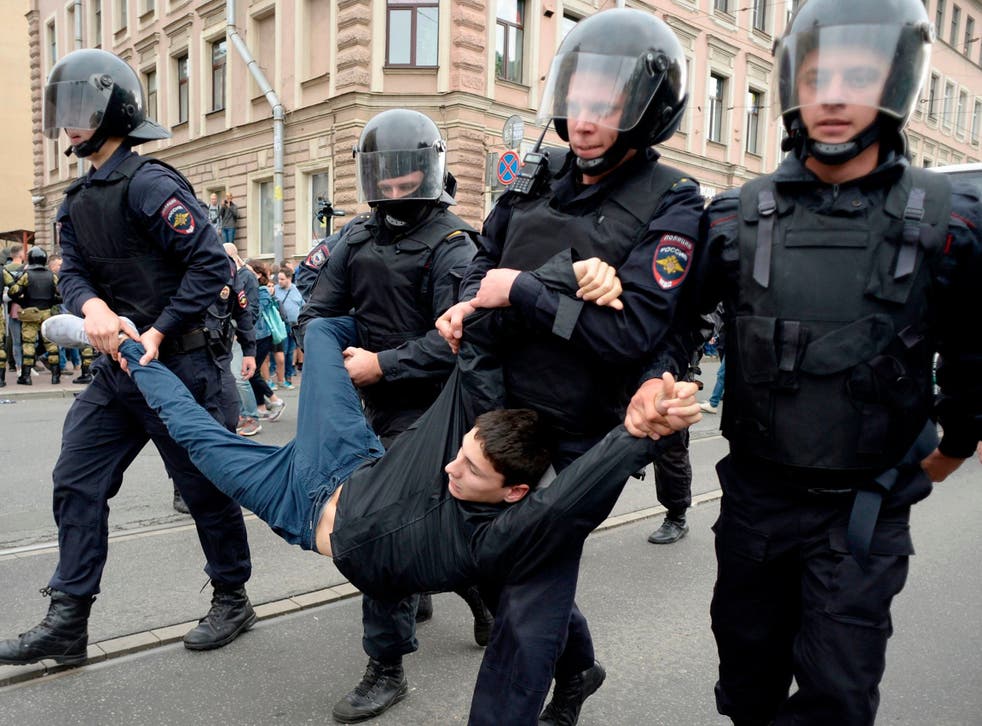 Police officers detain a young man during a protest rally against planned increases to the nationwide pension age in St Petersburg