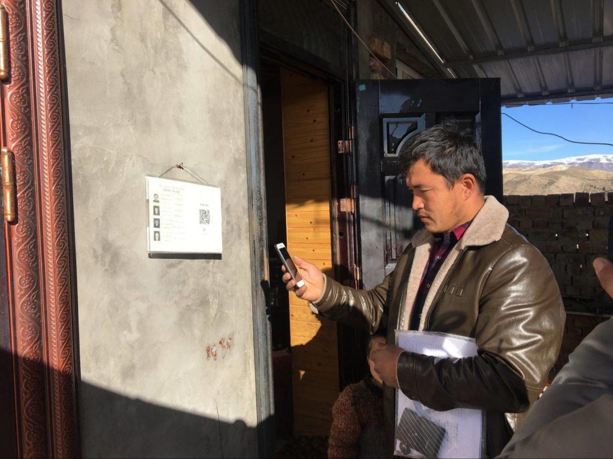A government official scans the code outside a home in Xinjiang province