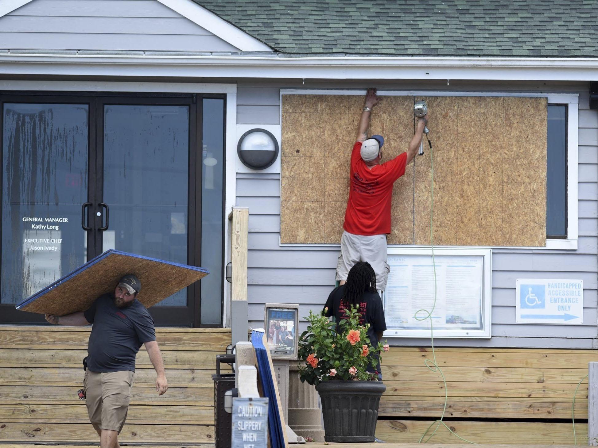 In this Tuesday, September 11, 2018, photo crews board up the Oceanic restaurant in Wrightsville Beach, N.C., in preparation for Hurricane Florence