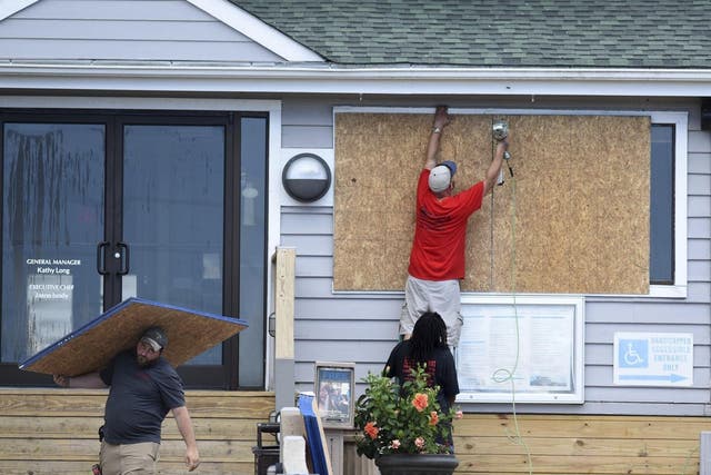 In this Tuesday, September 11, 2018, photo crews board up the Oceanic restaurant in Wrightsville Beach, N.C., in preparation for Hurricane Florence