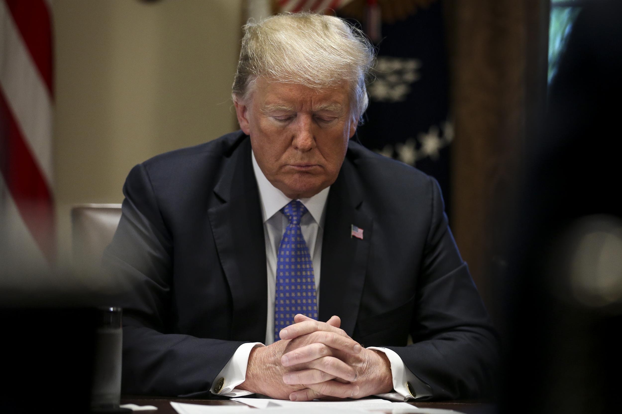 Donald Trump prays during a meeting with inner city pastors in the Cabinet Room of the White House on 1 August 2018 in Washington, DC.